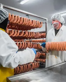Staff inspecting sausage links in USDA-inspected facility