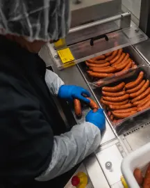 Personal manipulando salchichas en línea de producción