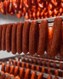 Salchichas colgadas en racks del ahumadero